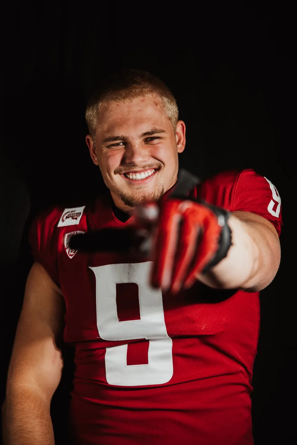 Washington State quarterback pointing forward in crimson jersey