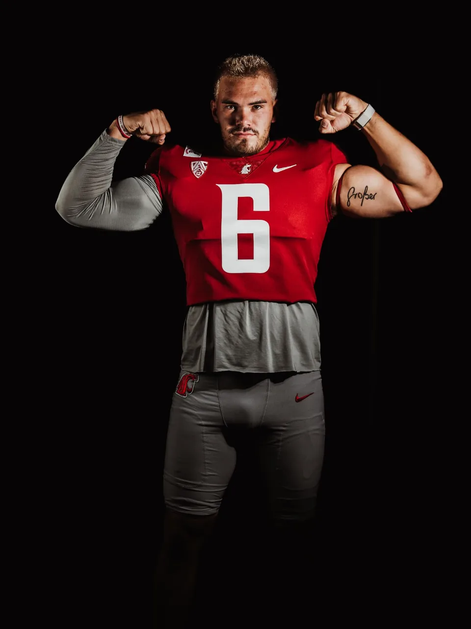 Washington State linebacker flexing in crimson jersey